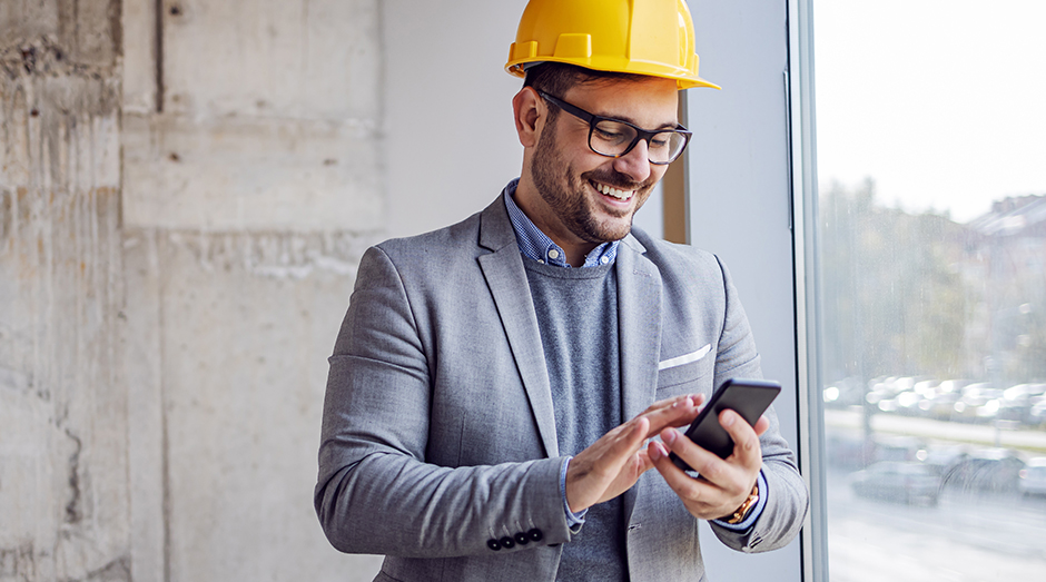 Business man with a hardhat and a mobile phone